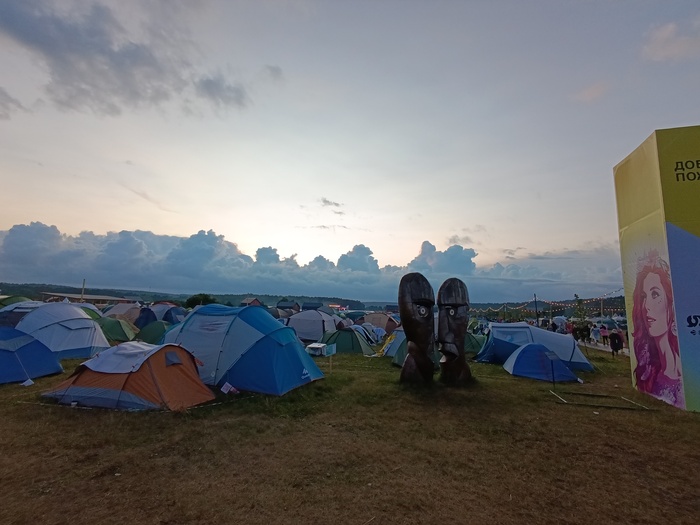 Облака и палатки лагеря Маяк рядом c инсталляцией двух голов с референсом на обложку альбома Division Bell группы Pink Floyd