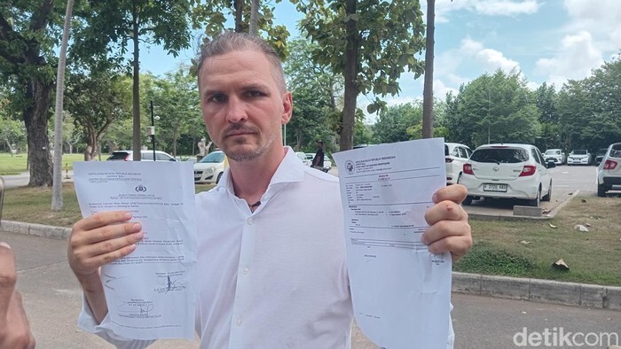 Сергей показывает полицейский отчёт и заключение экспертизы травм, полученных им во вторник (21 октября 2025 года).