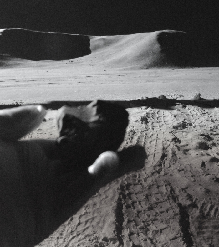 Поверхность луны астронавт рассматривает подобранный им с поверхности Луны камень.