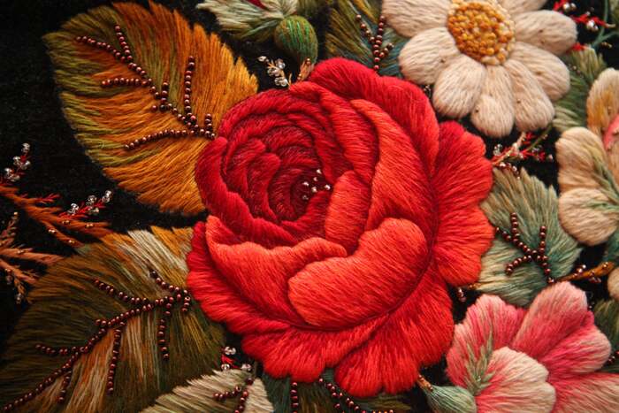 В красном бутоне, как и в розовом, использован один и тот же приём: края верхних лепестков вышиты объёмными, а к сердцевине они истончаются, и там, где тычинки бисера, всего один слой ниток.